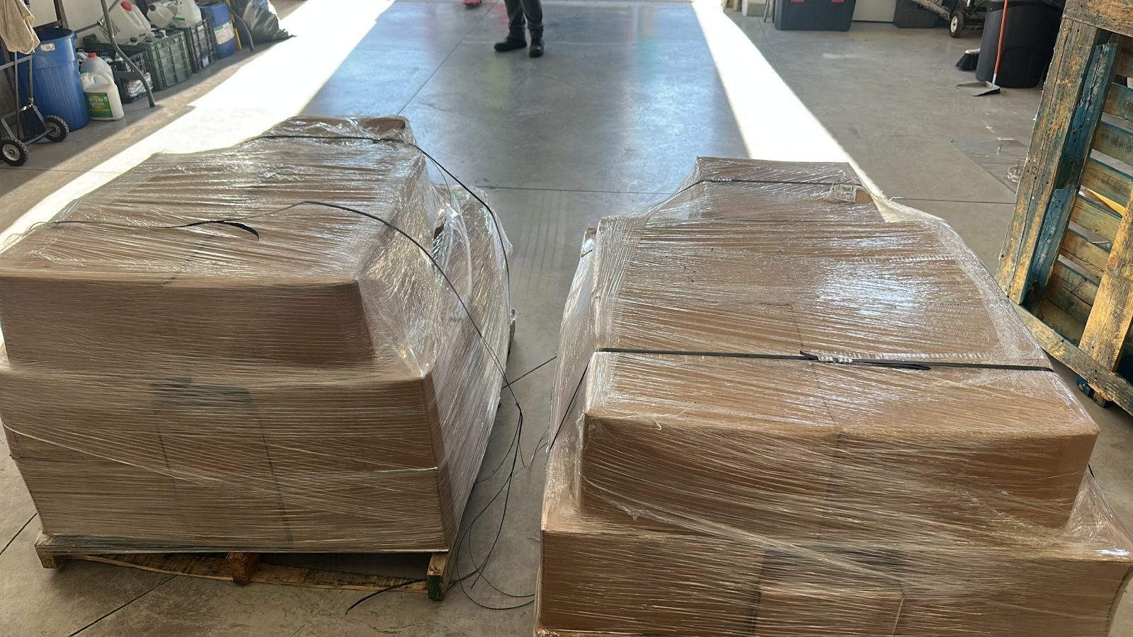 Dos tarimas emplayadas a contraluz en la puerta de la bodega, listas para salir